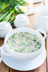 Traditional summer okroshka soup with sausage in a white bowl, selective focus