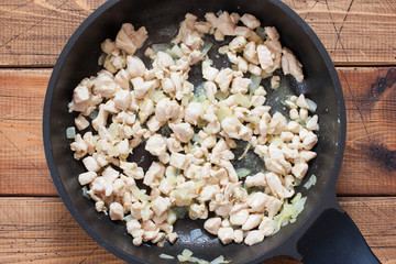 Step by step cooking risotto with mushrooms and chicken breast, step 3 - frying chicken fillet and onions, top view, selective focus
