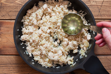 Step-by-step preparation of risotto with champignons and chicken breast, step 5 - adding chicken stock on a ladle, top view, selective focus