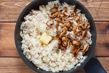 Step-by-step preparation of risotto with champignons and chicken breast, step 6 - adding fried champignons, butter, top view, selective focus
