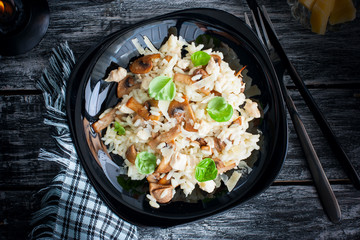 Traditional Italian risotto with chicken and mushrooms on a black plate, selective focus, top view