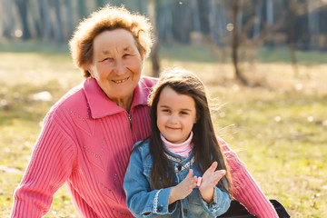 Obraz na płótnie Canvas Grandmother with granddaughter in park, spring