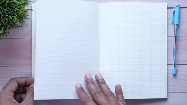 top view of man hand turning notepad pages.