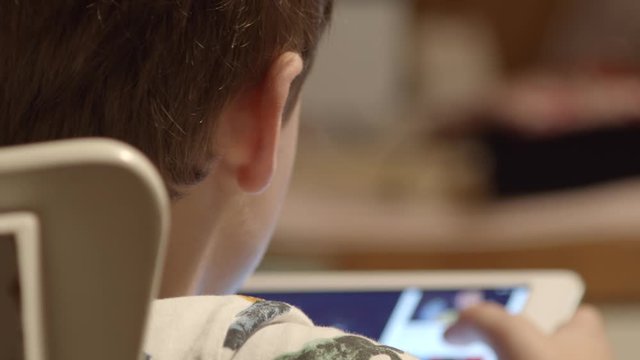 Over The Shoulder As Young Boy Watches Video On Tablet, Close-up