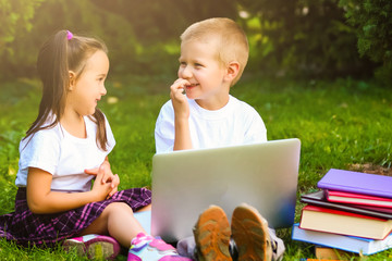 schoolboy and girl in park watching laptop