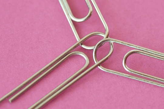 Three joined paper clips on pink background - Concept of unity and solidairity between women