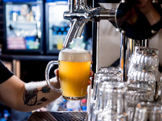 Bartender pouring draft beer at glasses in the bar. Restaurant.