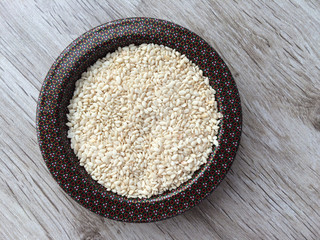 Close up of organic raw white sesame seeds in diah on wooden background.