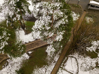 Flying over prak in the early spring. The snow is melting and the grass is green among the paths....