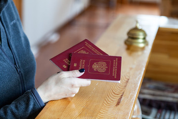 Female hand holds russian passport at wooden reception desk