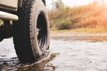 Part of the off-road vehicle parked in the river with warm light. adventure concep.off-road car. © PIPAT