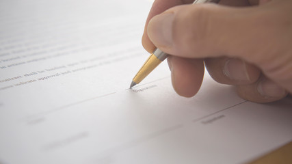 hand signing a document with pen. Signing a contract. Hand holding a pen.
