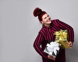 Obese lady in striped dress and earrings. Holding golden and silver gift boxes, overjoyed, posing...