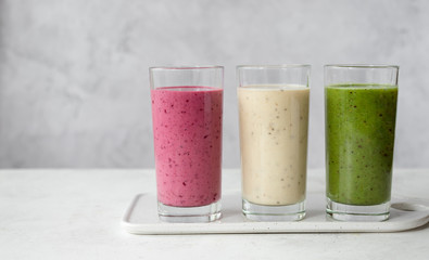 assortment of fruit and vegetable smoothies in glasses on a gray background. vitamin diet. banner,...