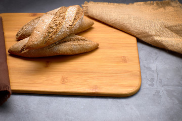 Delicious breads next to ears of wheat on a wooden board.