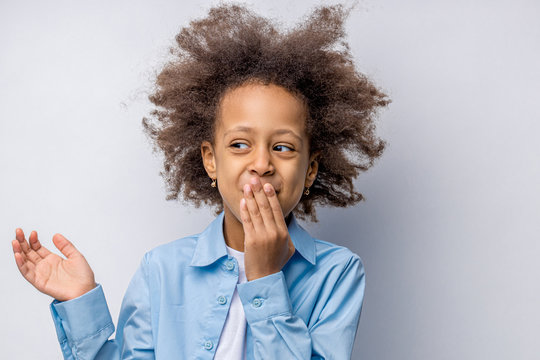 Emotional Portrait Of Positive Mulatto Girl With Hands On Mouth. Amazed Or Surprised Beautiful Schoolgirl Looking Side, She Is In Shock. Funny Cute Cheerful Child, Isolated On White Background