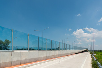 Fototapeta na wymiar Acrylic Noise Barrier, Transparent Noise Barrier Panels is installed at concrete bridge across the railway, Chon Buri, Thailand.