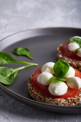 toasts with mozzarella, tomatoes and spinach in a gray plate