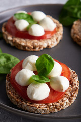 toasts with mozzarella, tomatoes and spinach in a gray plate