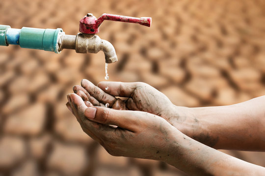 Hand of people wating for a drip of water from a faucet at desert. Climate change, water scarcity and crisis concept.