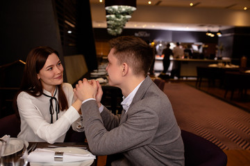 happy young caucasian couple enjoy dating in luxury restaurant. lady and guy look at each other with love. love, relationships, anniversary, romance concept