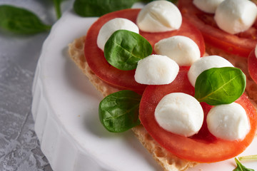 toasts with mozzarella, tomatoes and spinach in a white plate Close up