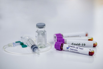 Blood sample tube of coronavirus or covid-19 disease with vaccine testing syringe. Medical and microbiologist science concepth photo.