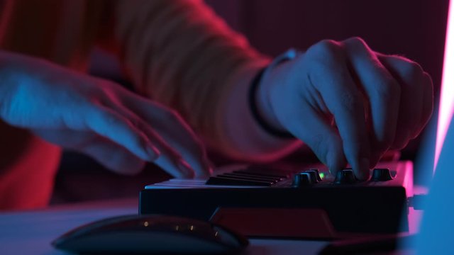 Male hands playing on piano electronic keyboard. Fingers tapping drum pads midi controller. Musician producing song at home recording studio. Sound maker create music melody. Online education. Closeup