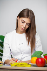 Obraz na płótnie Canvas Woman in the white coat nutritionist writes a healthy diet program for weight loss