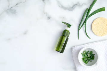 Green cosmetic bottle with aloe vera essential oil and sliced fresh leaves on marble background. Natural organic beauty product, skin care concept - Powered by Adobe