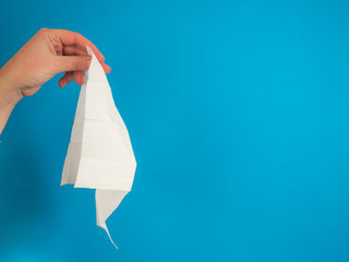 Hand with tissue on blue background with copy space