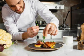 caucasian chef-cook finishing delicious dish in the kitchen of restaurant. expert in culinary. food concept