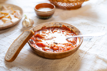 Ukrainian borsch well served with cream, garlic, salo - on white rustic tablecloth