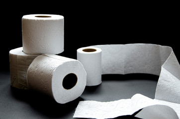 Rolls of white toilet paper lie on a black background