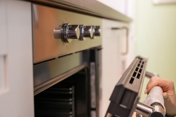Closeup of woman's hands open the oven. Housewife includes a built-in oven. unrecognizable girl is cooking pastries.