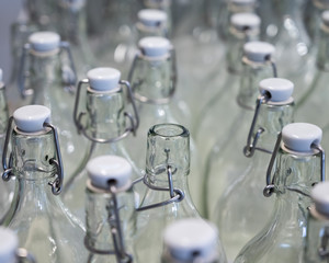 A closeup of the neck of a bottle. Group of empty bottles with plastic caps in a store on the counter.