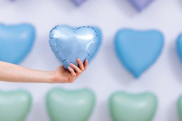 The woman holds the blue balloon in the form of a heart on many hearts background. valentines day. selective focus