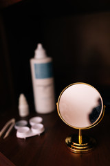 contact lenses for the eyes with mirror, bottle, tweezers and eye drops