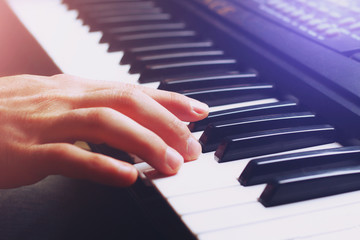 Musician's hand on the keys of a synthesizer, background, toned