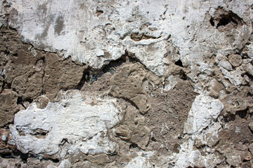 Cracks in the stucco on the wall of the house. Gray concrete in cracks  on whitewashed wall.