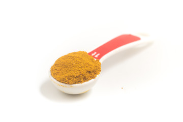Curry Powder into a teaspoon. Measuring spoon on white background
