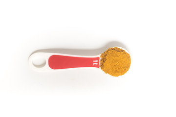 Curry Powder into a teaspoon. Measuring spoon on white background