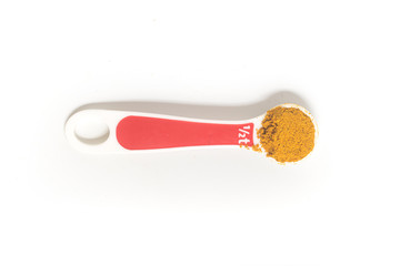 Curry Powder into a teaspoon. Measuring spoon on white background
