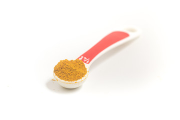 Curry Powder into a teaspoon. Measuring spoon on white background