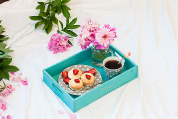 Breakfast in bed with cottage cheese pancakes, fresh strawberries, peonies and cup of coffee.