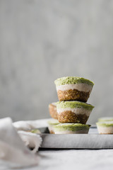 Stack of three healthy avocado and spinach coconut bites lactose and gluten free with white and light grey background