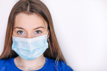 Head and shoulders portrait of female doctor wearing protective mask and looking at camera posing against white background, copy space