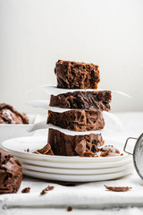 Healthy baked homemade brownies stacked on top of each other on four white plates and white...