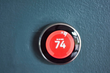 Nest smart home thermostat with red center in heat mode. Saving energy heating home. Isolated...