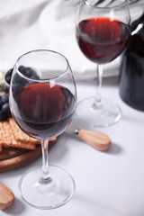 Two glasses of red wine and plate with assorted cheese, fruit and other snacks for party